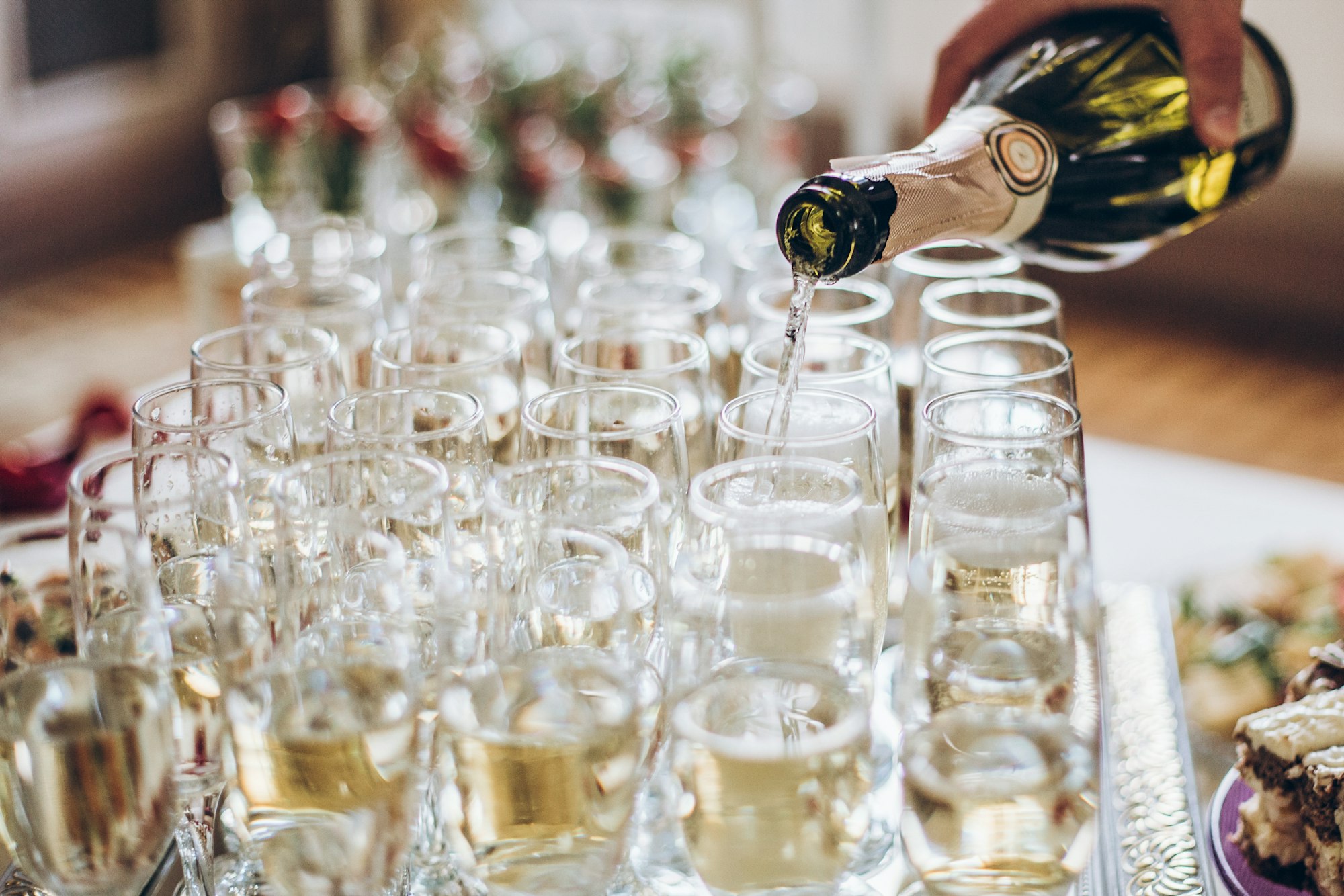 Waiter pouring champagne in stylish glasses at luxury wedding reception